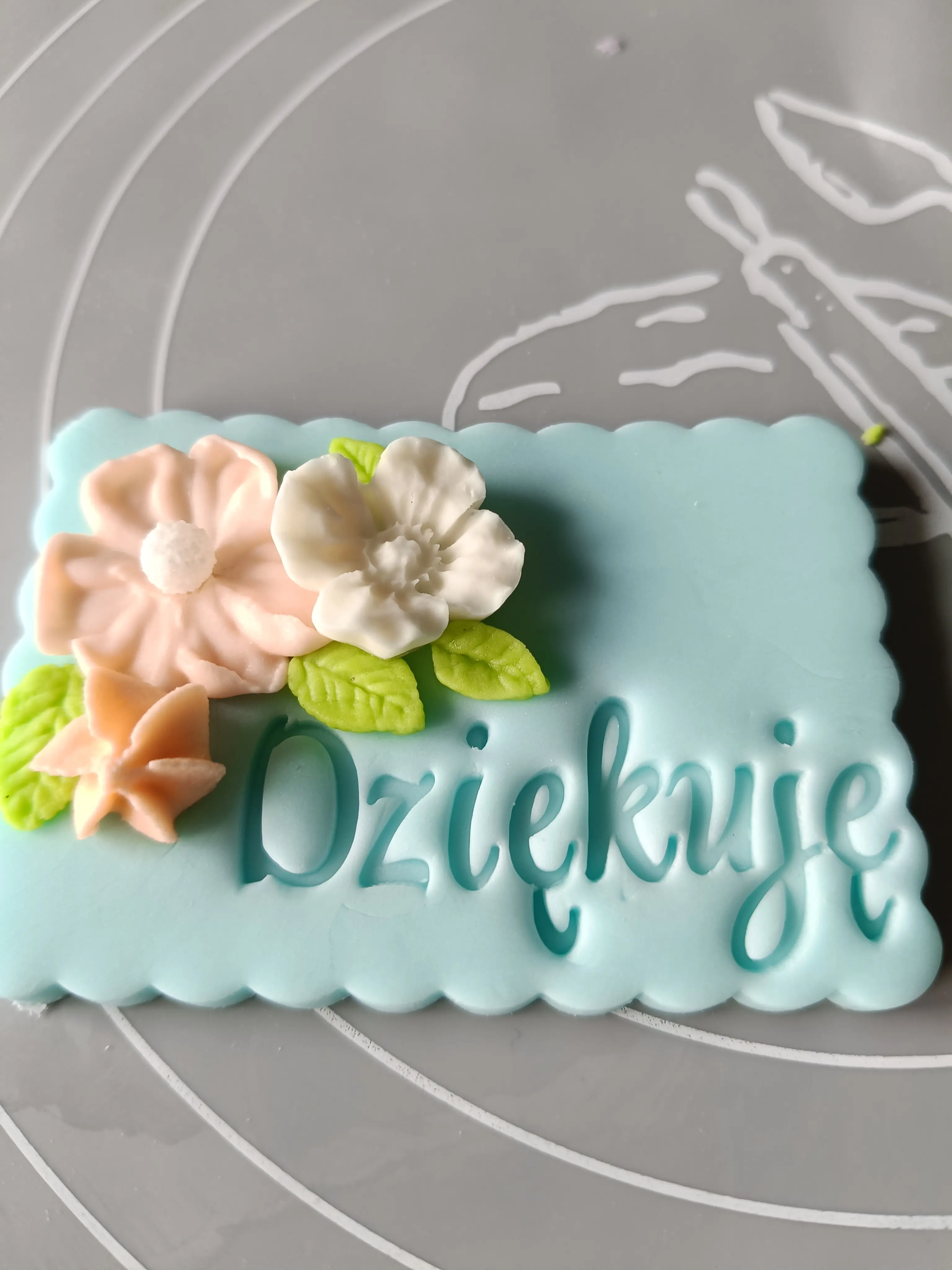 Personalizowane ciasteczko lukrowe z napisem Dziękuję – niebieska tabliczka z kwiatową dekoracją, idealne jako słodki upominek