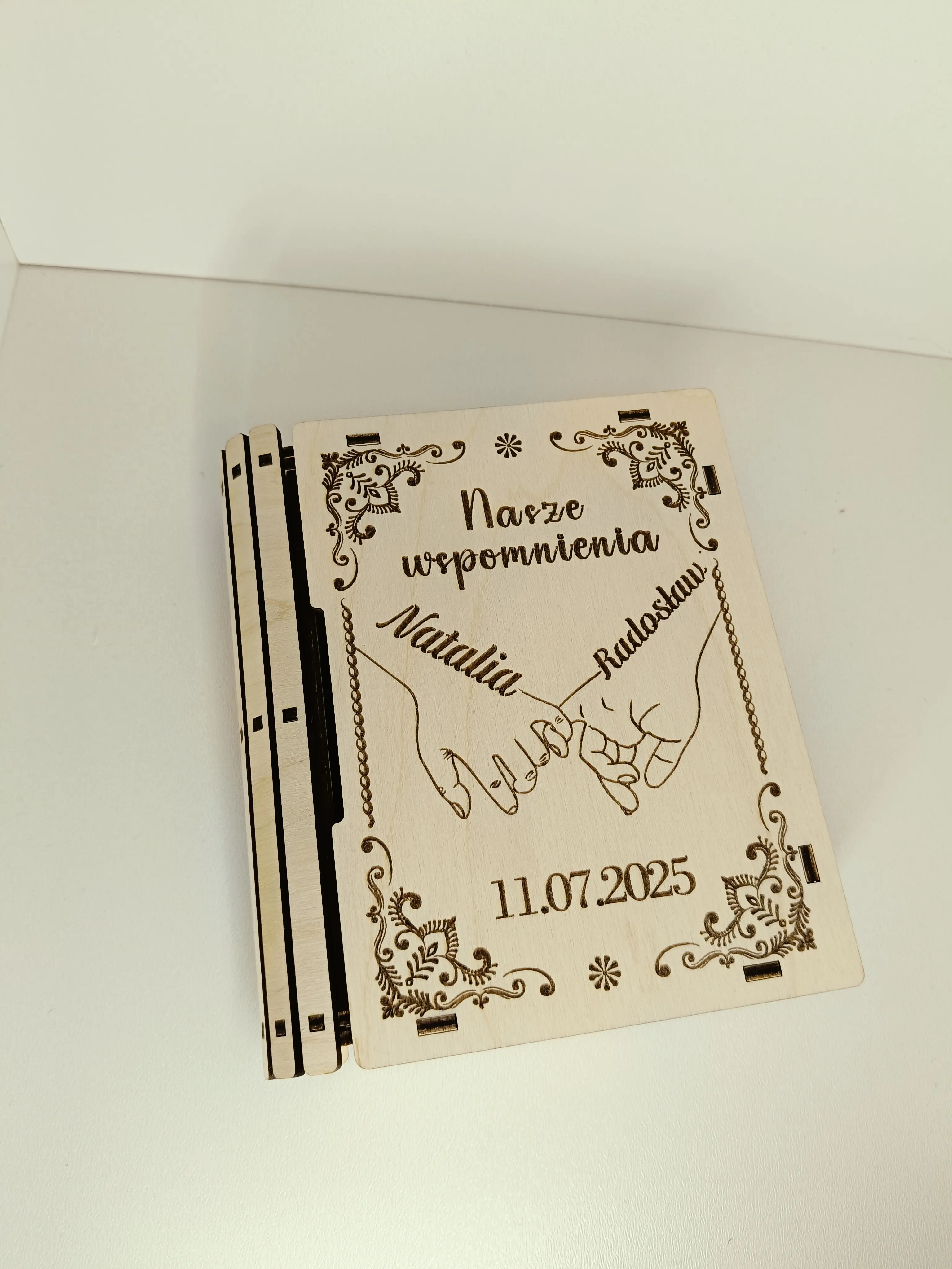 Drewniane pudełko wspomnień z grawerem Nasze wspomnienia, imionami Natalia & Radosław, datą 11.07.2025 oraz motywem splecionych dłoni i kwiatowym ornamentem