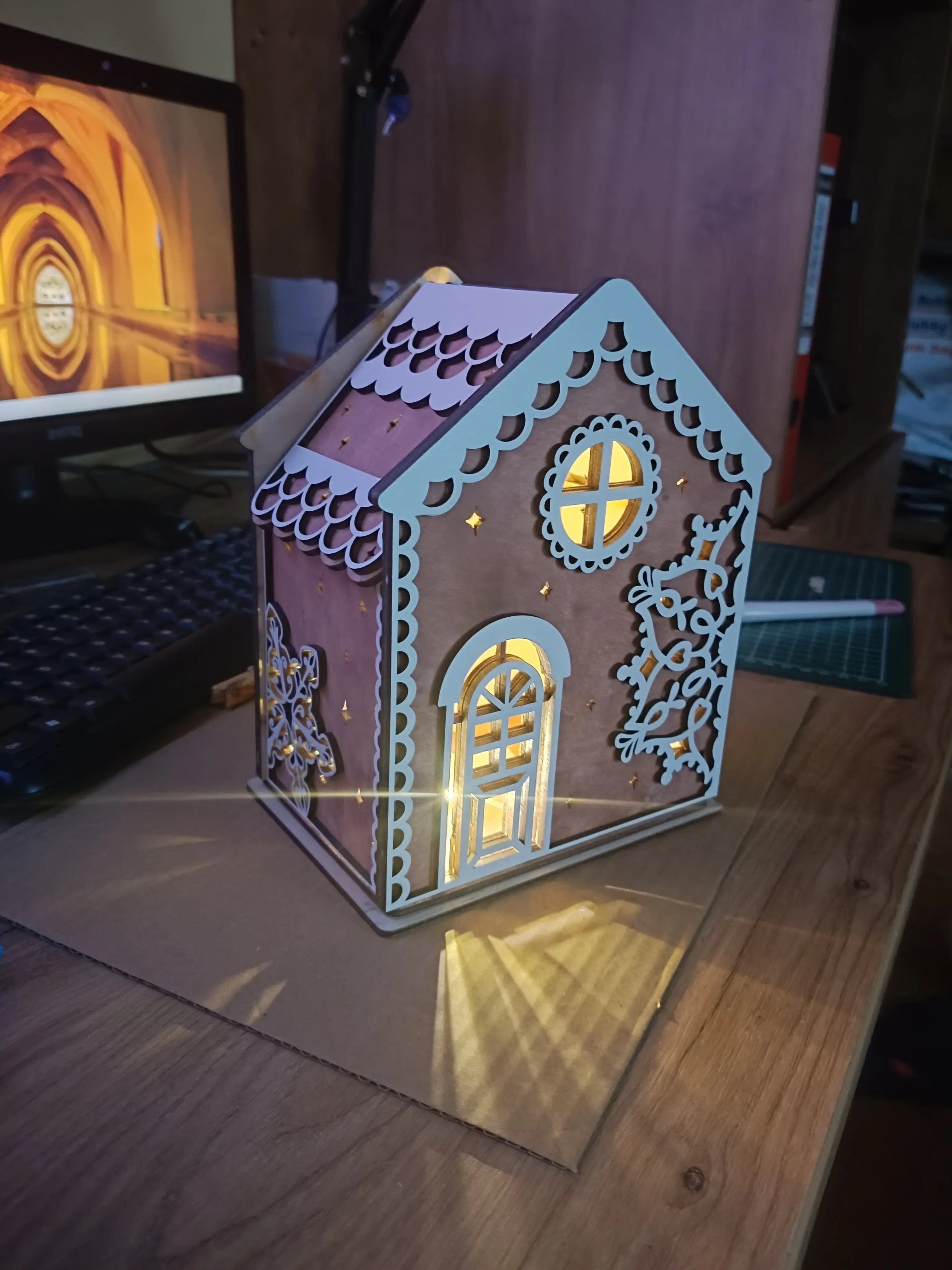 Drewniany domek świąteczny z podświetleniem LED, ozdobiony wyciętymi gwiazdkami, okienkami