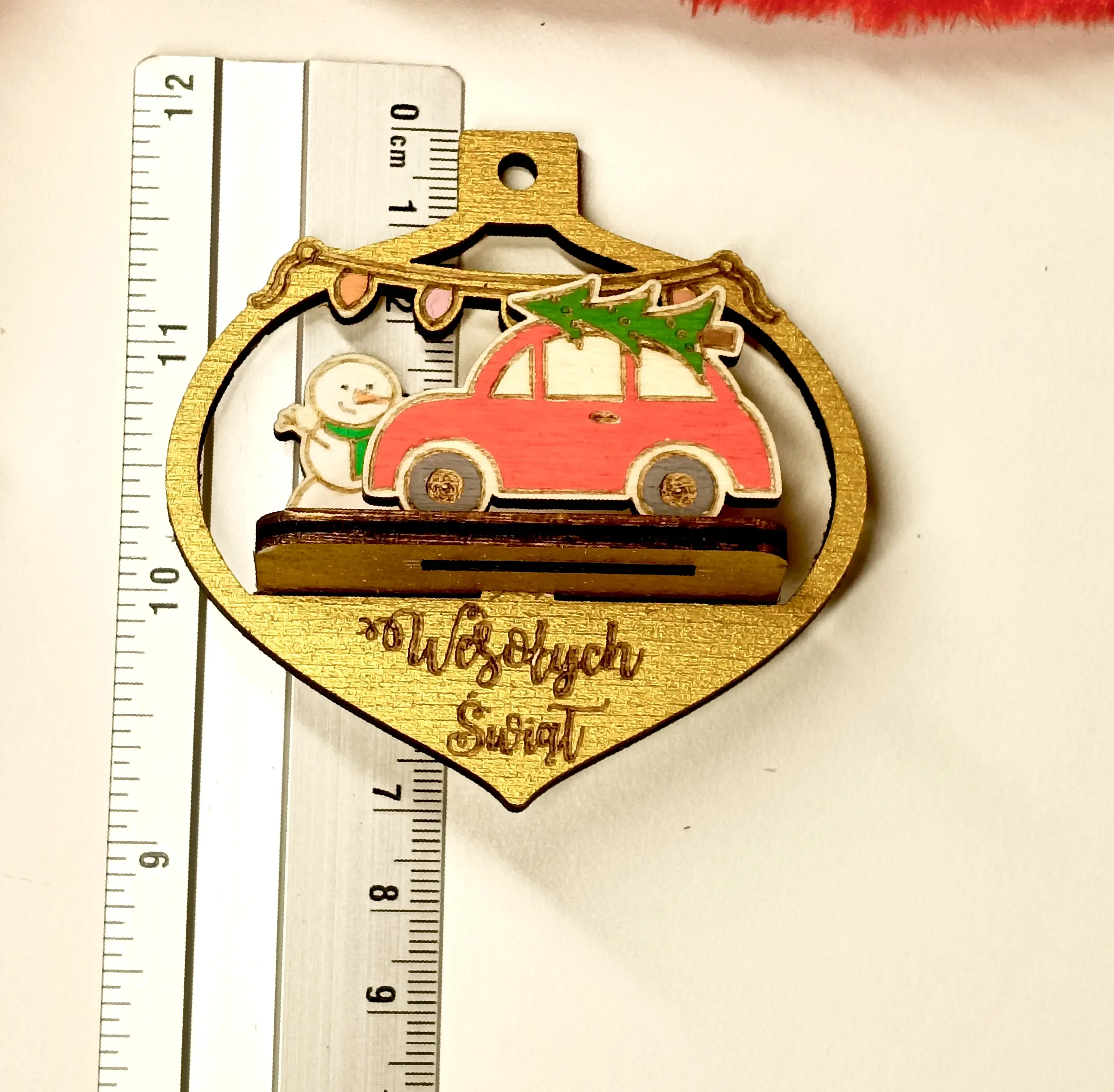 Drewniana bombka świąteczna w kształcie łezki z czerwonym samochodem, choinką, bałwanem i lampkami