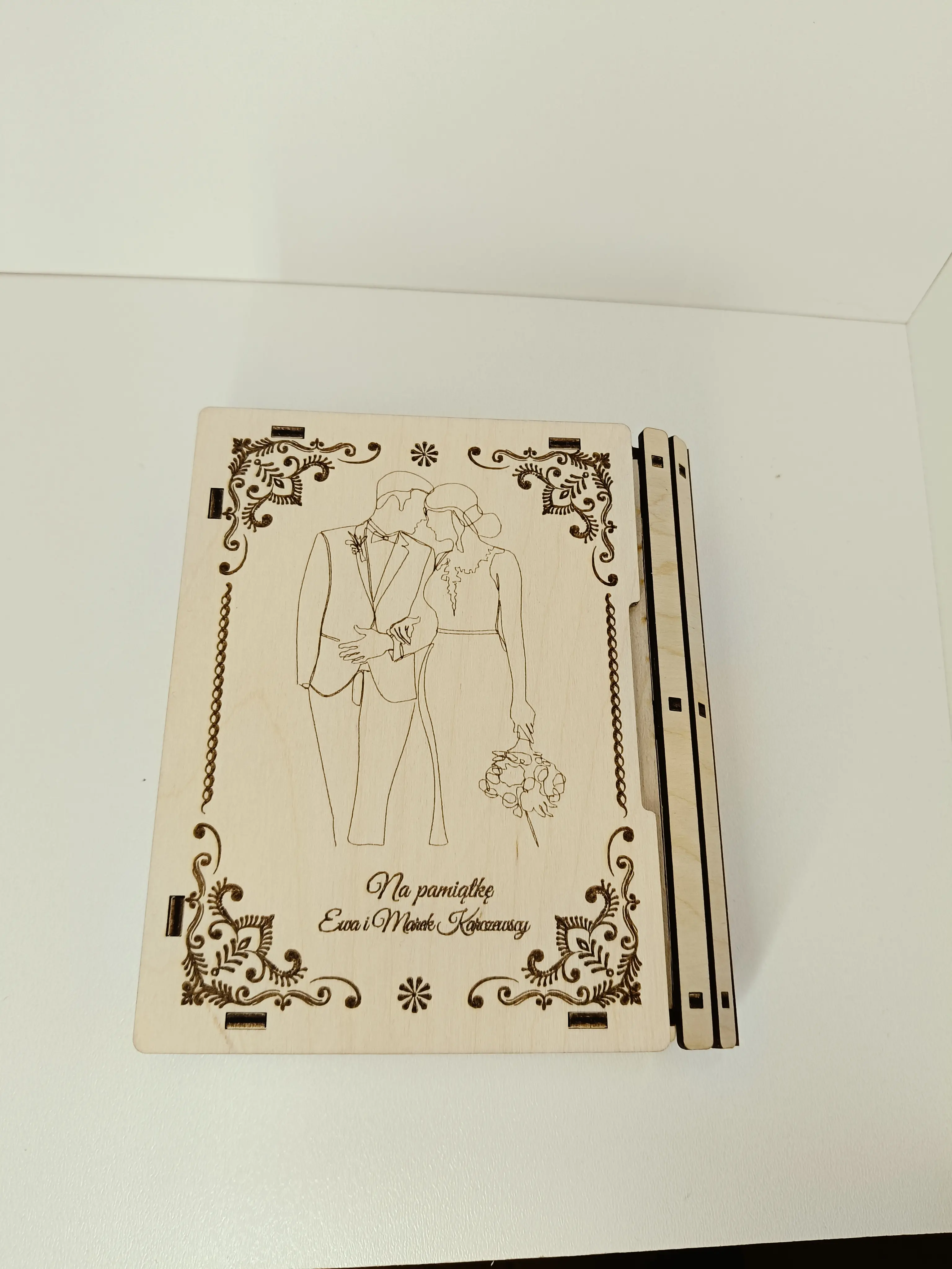 Drewniana tablica pamiątkowa z grawerem pary młodej, ornamentami kwiatowymi i napisem Na pamiątkę Ewa i Marek Kowalscy w Ełku
