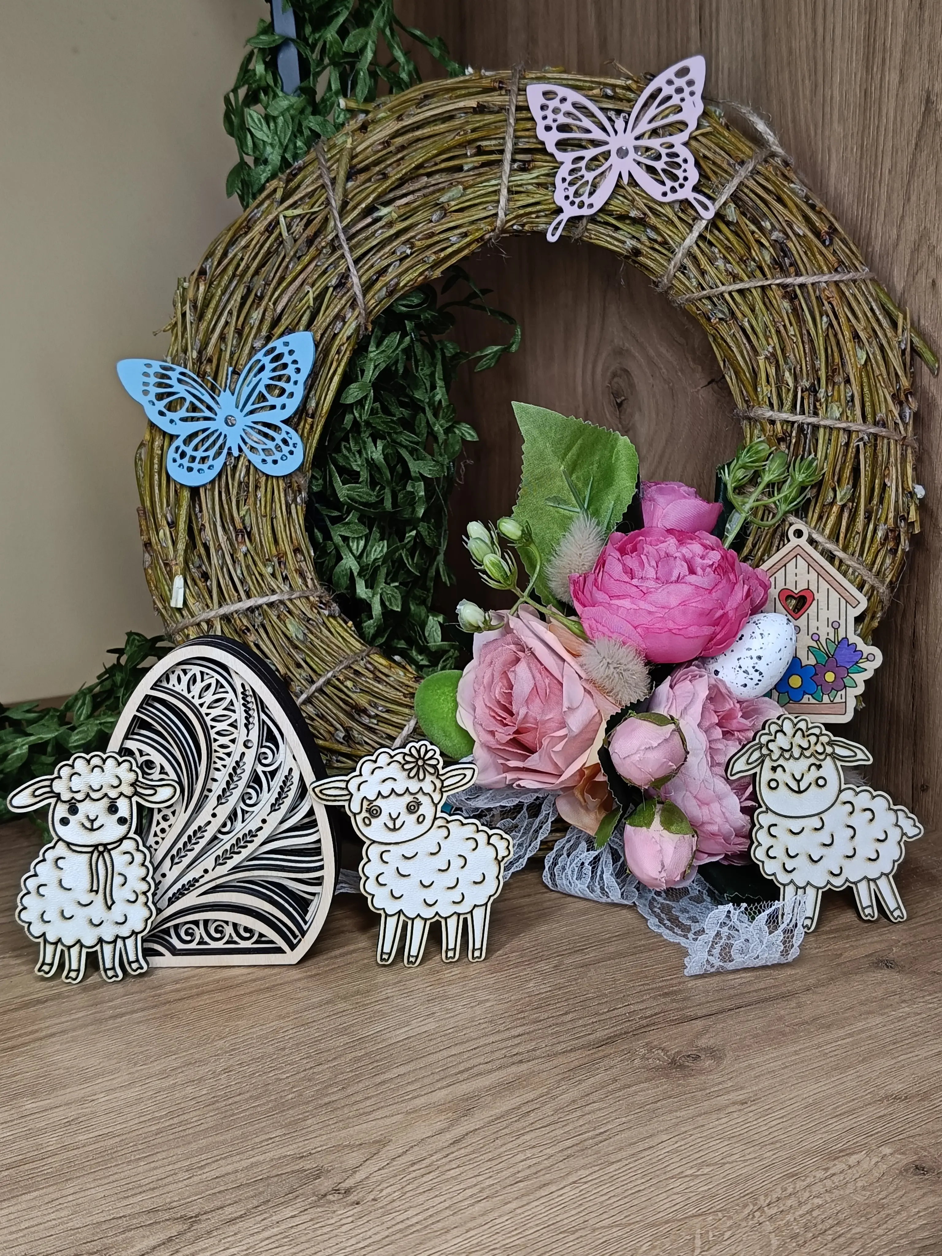 Rustykalna dekoracja wielkanocna z wiankiem, bukietem róż, trzema owieczkami i drewnianymi ozdobami